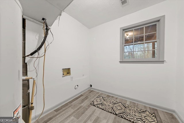 laundry room with a textured ceiling, hookup for an electric dryer, hookup for a washing machine, and light hardwood / wood-style flooring