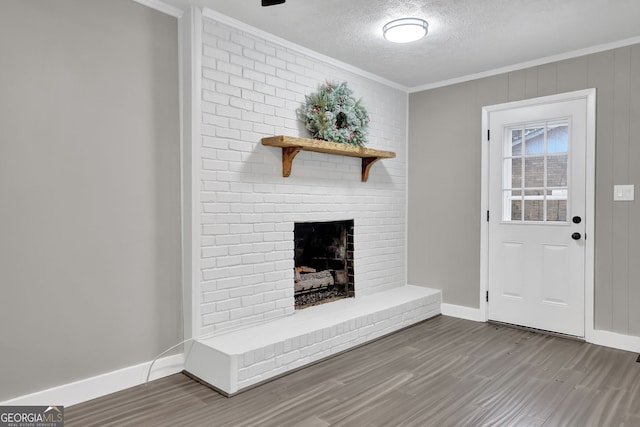 unfurnished living room featuring a textured ceiling, crown molding, a fireplace, and wood-type flooring