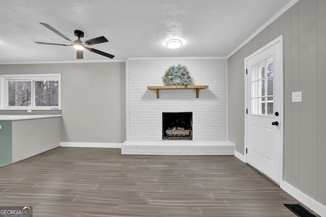 unfurnished living room featuring a fireplace, a wealth of natural light, crown molding, and dark hardwood / wood-style floors