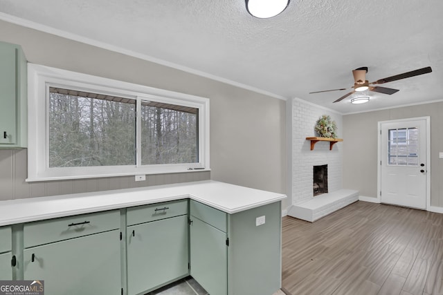 kitchen featuring a brick fireplace, green cabinets, crown molding, and a textured ceiling