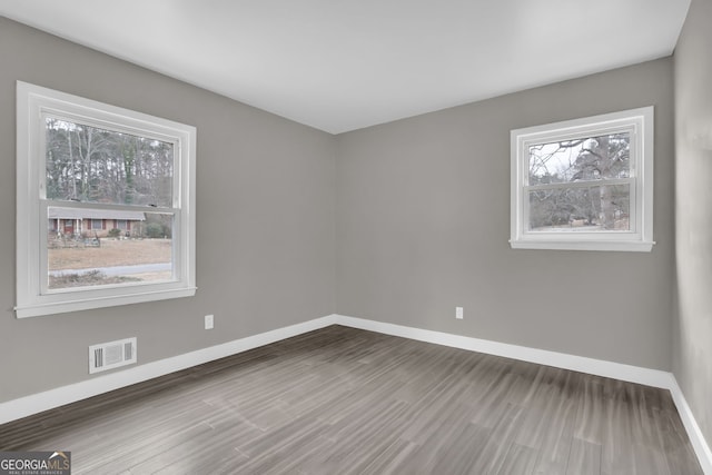 unfurnished room featuring a healthy amount of sunlight and hardwood / wood-style flooring