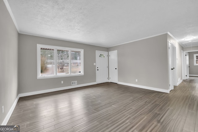 unfurnished living room featuring a textured ceiling, dark hardwood / wood-style flooring, and ornamental molding