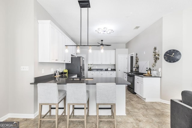 kitchen with white cabinets, decorative light fixtures, black gas range oven, kitchen peninsula, and stainless steel refrigerator