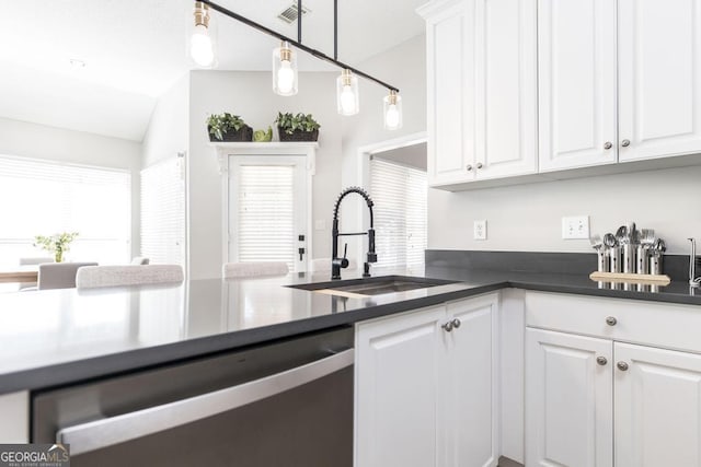 kitchen with decorative light fixtures, lofted ceiling, stainless steel dishwasher, sink, and white cabinets