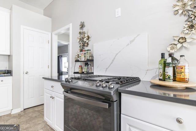 kitchen with stainless steel gas range, white cabinetry, and backsplash