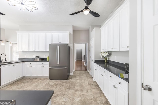 kitchen with ceiling fan, sink, stainless steel refrigerator, and white cabinetry