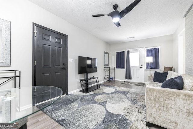 living room featuring a textured ceiling, ceiling fan, and hardwood / wood-style flooring