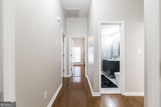 corridor featuring a high ceiling, sink, and dark hardwood / wood-style floors