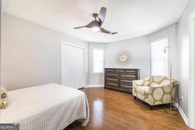 bedroom with ceiling fan, a closet, a textured ceiling, and wood-type flooring