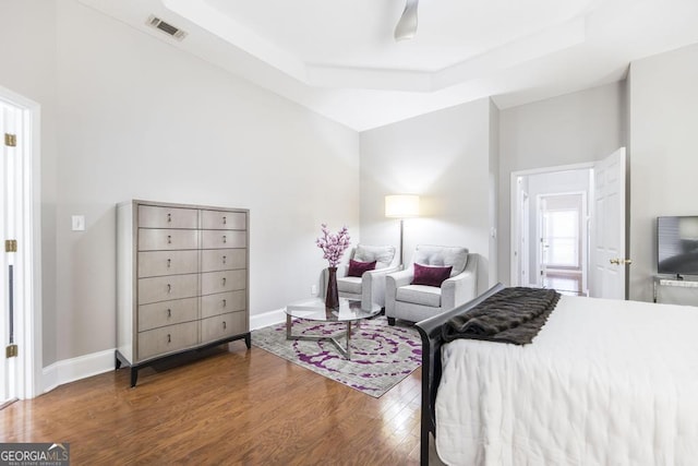 bedroom with wood-type flooring and a raised ceiling