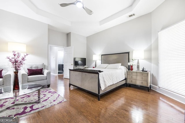 bedroom featuring a raised ceiling, ceiling fan, and dark wood-type flooring