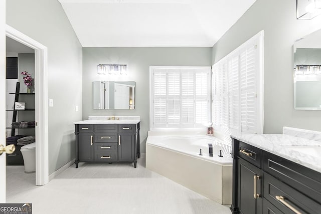 bathroom with vanity, a bathtub, vaulted ceiling, and tile patterned floors