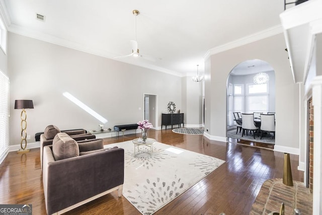 living room with dark hardwood / wood-style floors, ceiling fan with notable chandelier, and ornamental molding