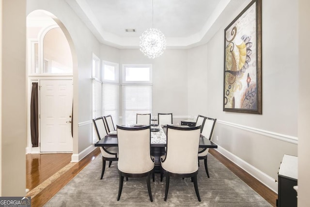 dining room featuring dark hardwood / wood-style floors, a tray ceiling, and a notable chandelier