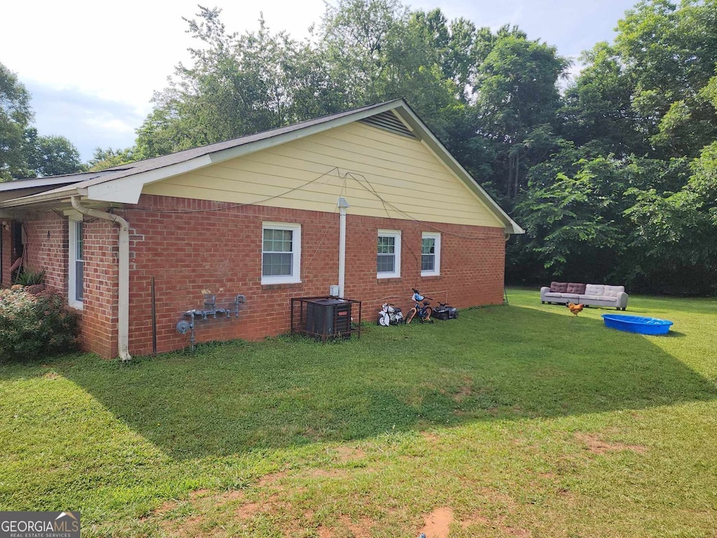 view of side of property featuring a lawn and central AC