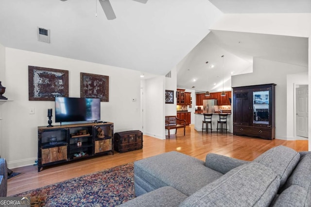 living room featuring ceiling fan, light hardwood / wood-style flooring, and lofted ceiling