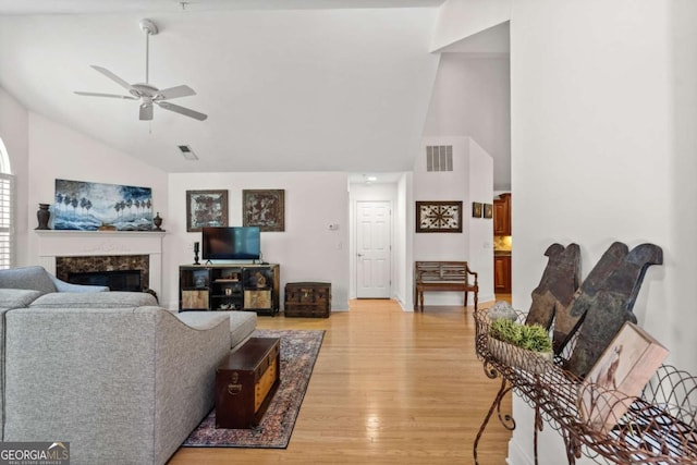 living room featuring hardwood / wood-style flooring, high vaulted ceiling, ceiling fan, and a fireplace