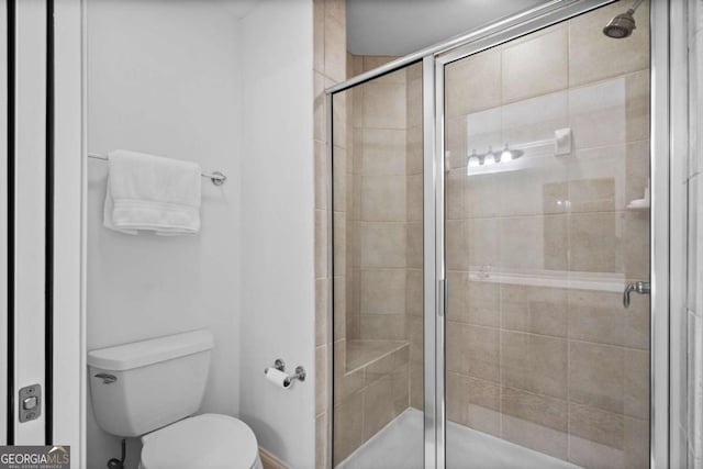 bathroom with toilet and a shower with shower door