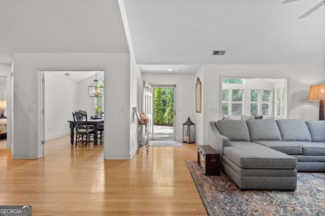 living room with ceiling fan with notable chandelier and light hardwood / wood-style floors