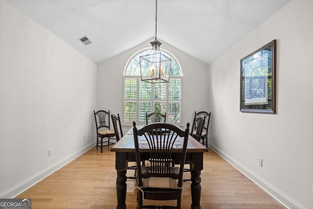 dining space with light hardwood / wood-style flooring, an inviting chandelier, and vaulted ceiling