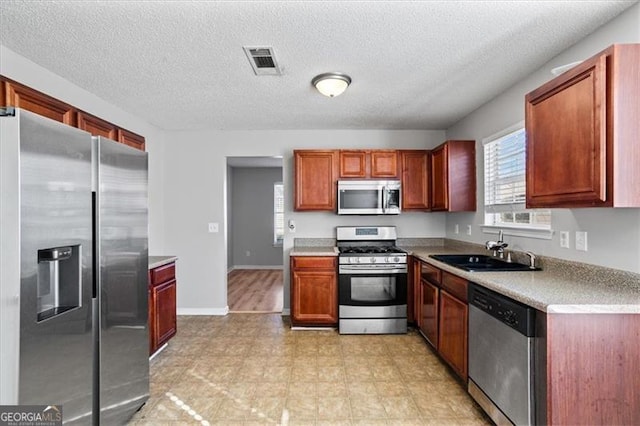 kitchen with sink, a textured ceiling, and appliances with stainless steel finishes