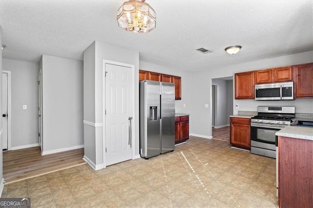 kitchen with hanging light fixtures, stainless steel appliances, and a textured ceiling