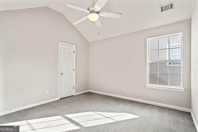 spare room with ceiling fan, vaulted ceiling, and carpet