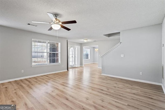 unfurnished living room with a textured ceiling, ceiling fan with notable chandelier, and light hardwood / wood-style flooring