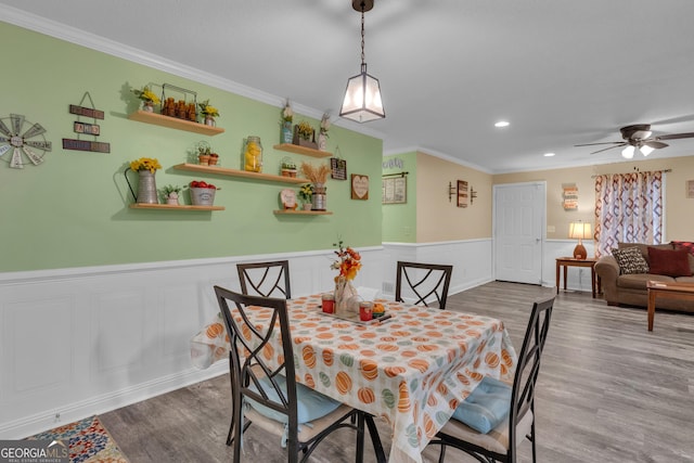 dining area featuring crown molding, wood-type flooring, and ceiling fan