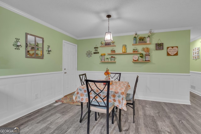 dining area with wood-type flooring and ornamental molding