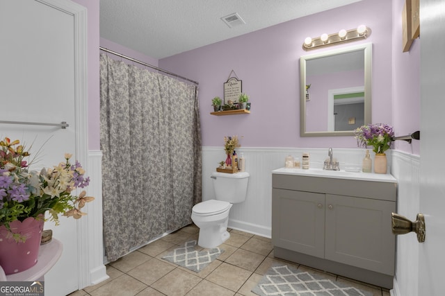 bathroom with vanity, tile patterned floors, toilet, and a textured ceiling