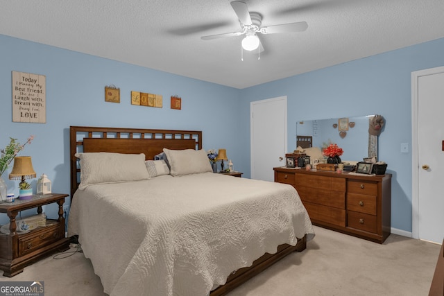 carpeted bedroom featuring ceiling fan and a textured ceiling