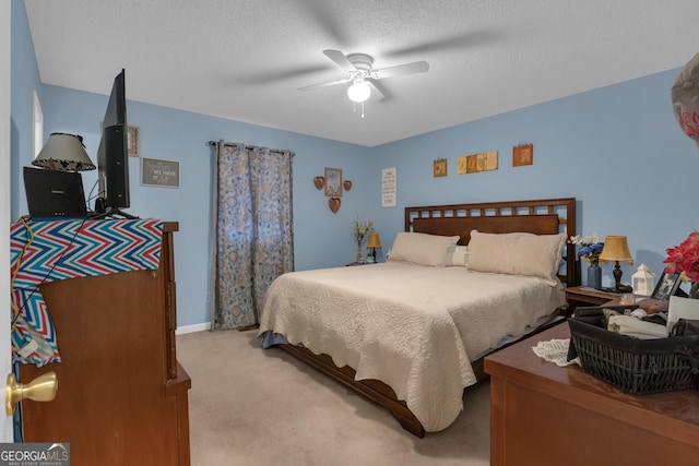 bedroom featuring ceiling fan, light colored carpet, and a textured ceiling