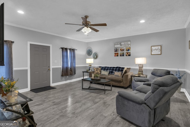 living room featuring hardwood / wood-style flooring, ceiling fan, ornamental molding, and a textured ceiling