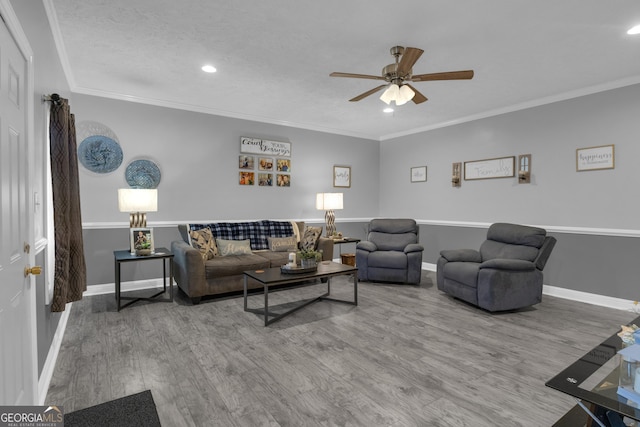 living room with hardwood / wood-style flooring, ornamental molding, and ceiling fan