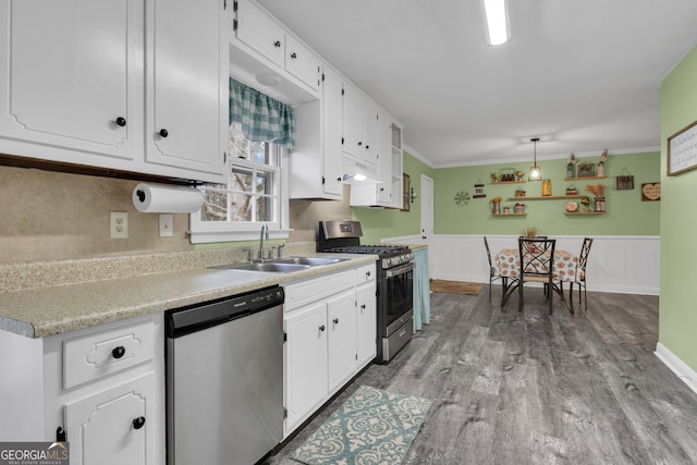 kitchen with appliances with stainless steel finishes, pendant lighting, white cabinetry, sink, and light wood-type flooring