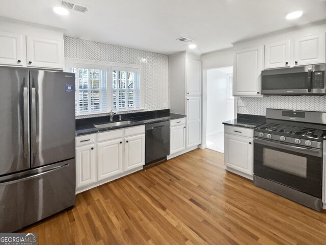 kitchen featuring hardwood / wood-style flooring, appliances with stainless steel finishes, white cabinetry, and sink