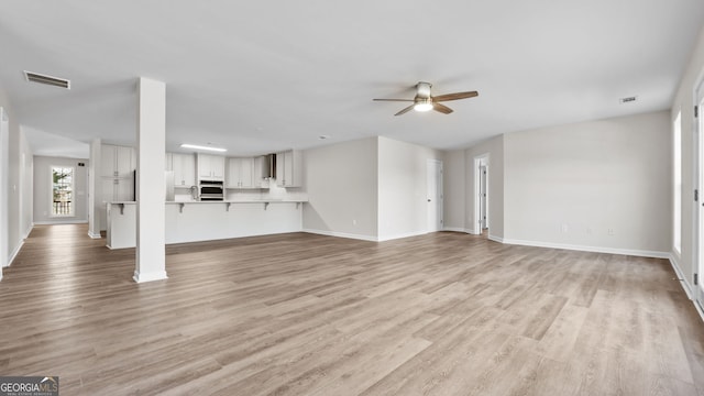 unfurnished living room with light wood-type flooring and ceiling fan