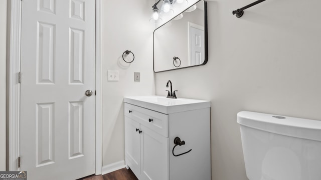 bathroom featuring toilet, wood-type flooring, and vanity