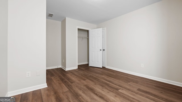 unfurnished bedroom with dark hardwood / wood-style floors and a closet