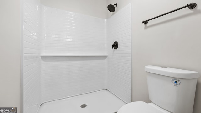 bathroom with a tile shower and toilet