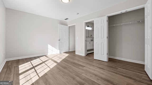 unfurnished bedroom featuring a closet, connected bathroom, and dark hardwood / wood-style floors