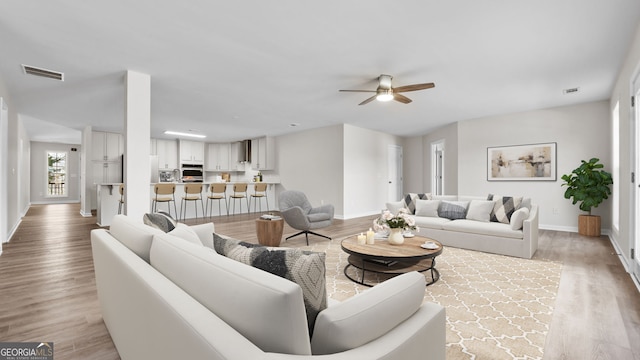 living room featuring ceiling fan and light hardwood / wood-style flooring