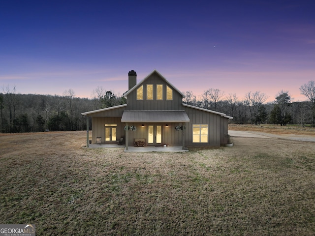 back house at dusk with a patio area and a yard