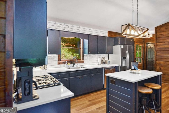 kitchen with appliances with stainless steel finishes, backsplash, decorative light fixtures, sink, and a center island