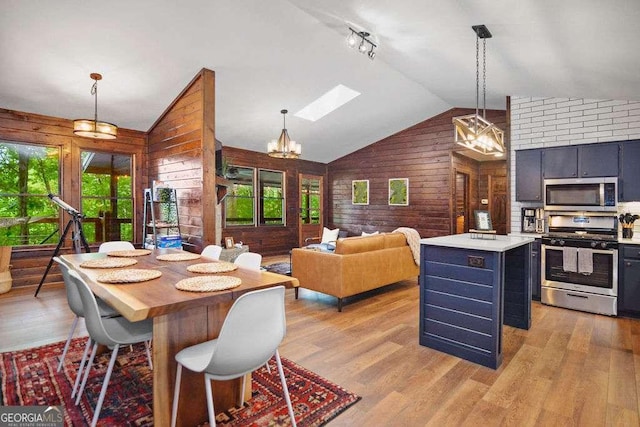 dining area featuring plenty of natural light, vaulted ceiling with skylight, and light hardwood / wood-style flooring