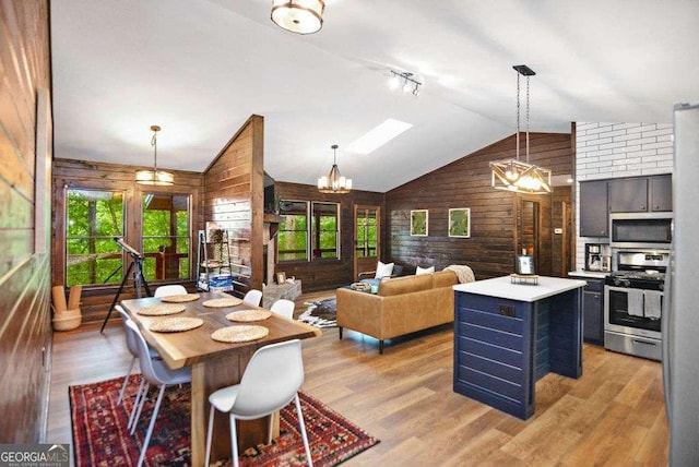 dining room featuring light wood-type flooring, lofted ceiling with skylight, and wooden walls