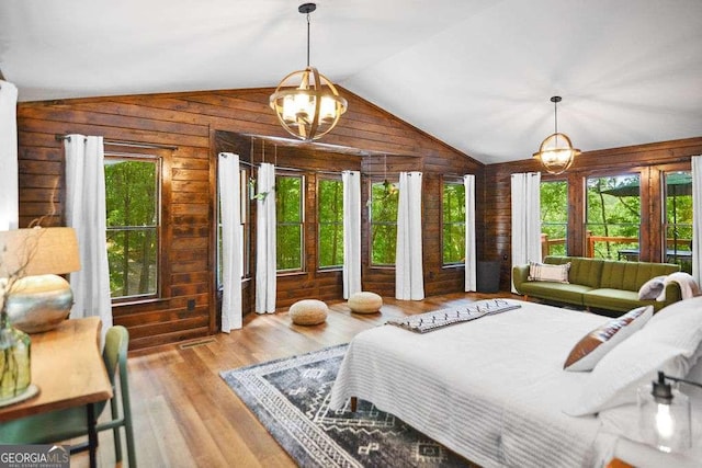 bedroom with multiple windows, light wood-type flooring, wood walls, and an inviting chandelier