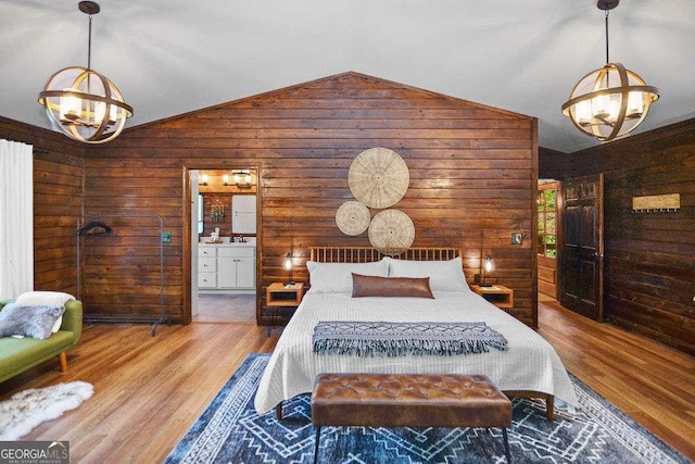 bedroom with vaulted ceiling, wood walls, ensuite bath, wood-type flooring, and an inviting chandelier