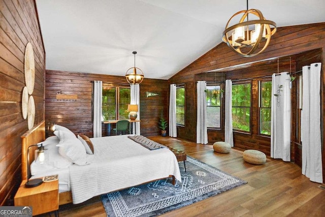 bedroom featuring vaulted ceiling, a chandelier, wood-type flooring, and wood walls